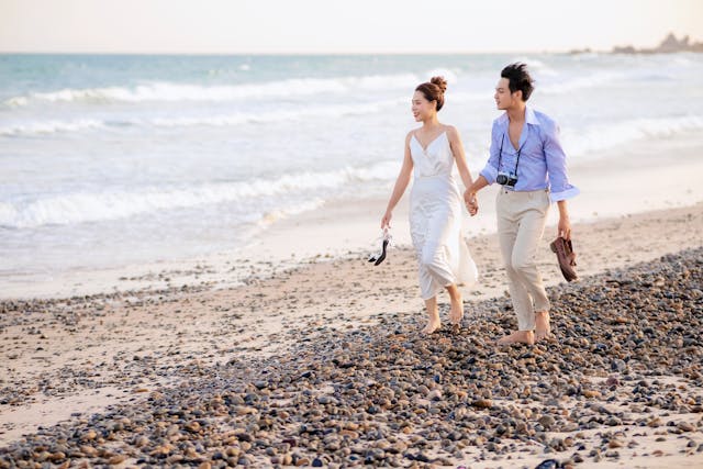 A couple walks barefoot along a rocky beach, enjoying a peaceful moment, showing the relaxed lifestyle often found in Florida's best walkable communities